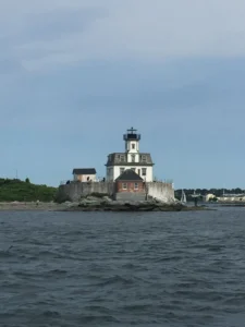 A lighthouse on the water with trees in the background