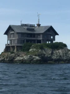 A house on top of a rock island in the ocean.