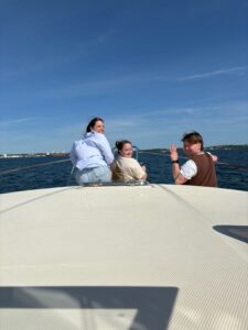 Three people sitting on the bow of a boat.