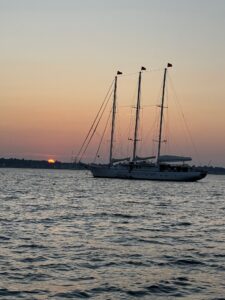 A boat is sailing in the ocean at sunset.