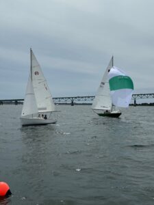 Two sail boats in the water near a bridge.