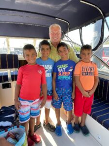 A group of kids standing on the back of a boat.